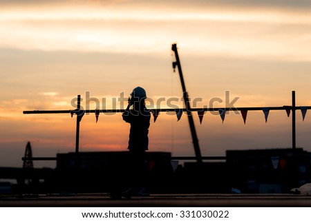 Construction site, silhouettes of engineer people or workers on scaffolding against the twilight.