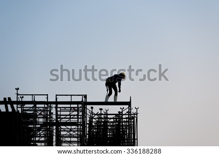 Silhouette of construction worker non safety on scaffolding in the construction site before to night time.