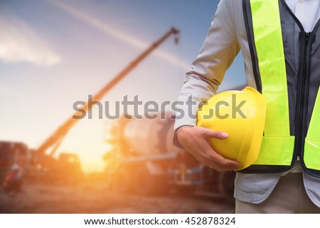 Engineer or Safety officer holding hard hat with the mobile crane machine is background in construction site.