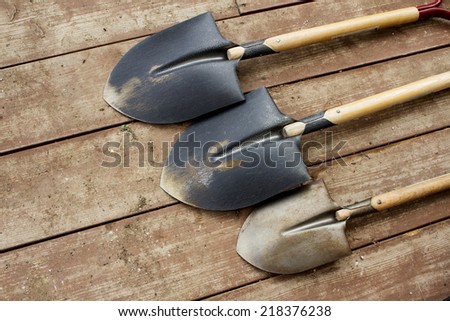 Three different size of soil shovel on the wood floor after gadening in the flower garden.