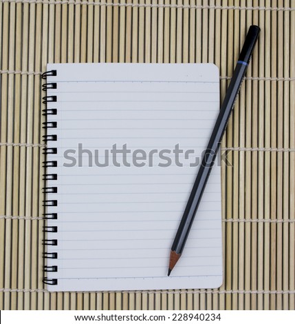 blank realistic spiral notepad notebook with pencil on brown bamboo background