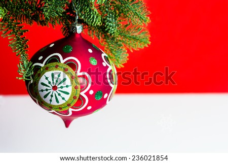 Christmas ball  ornament hanging on Christmas tree branch on a bright red and white  background