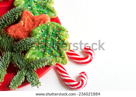 Christmas cookies with peppermint candy canes in red plate isolated over white background. Christmas cookies with festive decoration