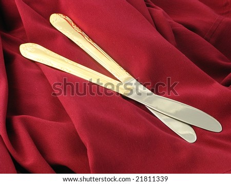 Abstract Shiny Gold Knives Arranged and Isolated on a Dark Red Burgundy Background as a Closeup