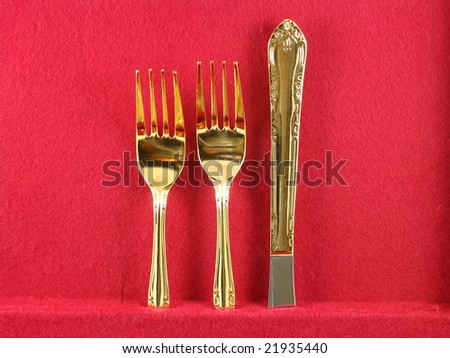 Shiny Gold Dinnerware Forks and Knife Arranged and Isolated on a Dark Red Burgundy Background as an Abstract Closeup