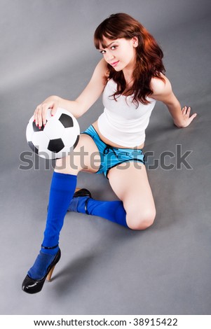 Pretty girl sitting on the floor and holding a soccer ball.