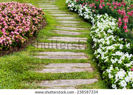 Walkway in garden made from old wooden with green grass and flowers