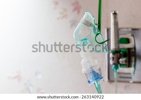 Close-up image of a medical oxygen mask and valve setting blurry on wall