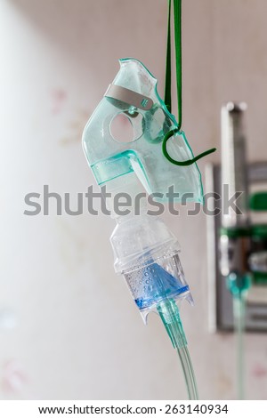 Close-up image of a medical oxygen mask and valve setting blurry on wall