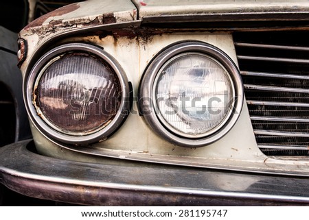 Detail of the front headlight of an old car in garage