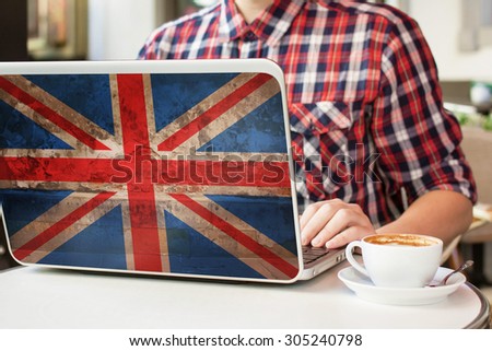 Man sitting in a cafe with cup of coffee and notebook with flag of Great Britain on it. English language learning concept