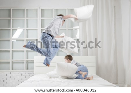 Young children playing on the bed. Pillow fight