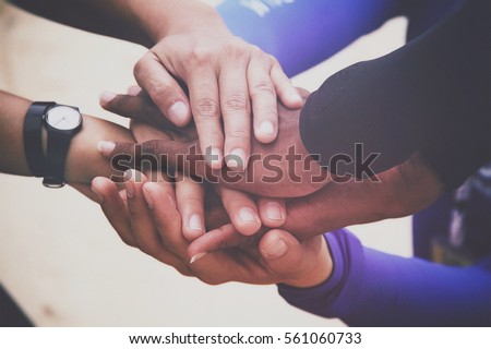 Diverse group of people joining hands in supportive gesture
