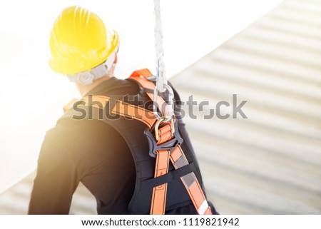 Industrial Worker with safety protective equipment loop hanging on the back sitting above the container, safety concept