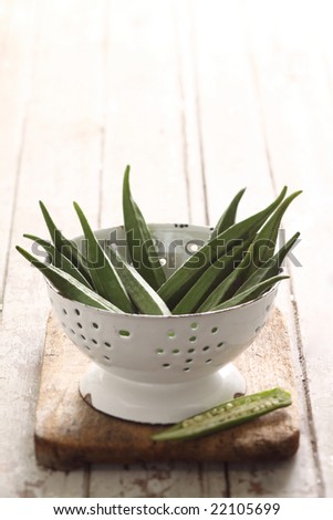green okra, organic vegetable in a white retro cup. see texture of old wood background.