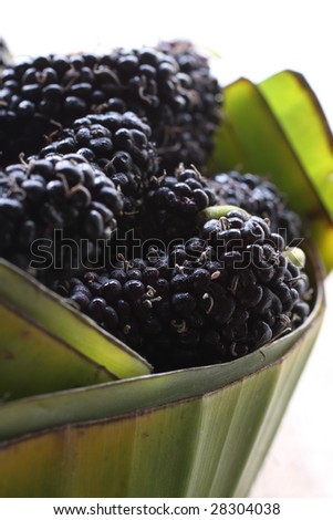 pile of black mulberry, closeup texture, in a banana leave basket.