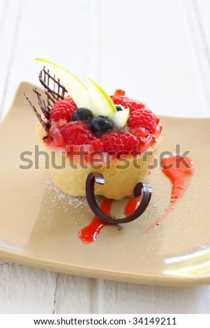 fruit tart with fresh fruit like kiwi, blueberry, raspberry cherry, styling with chocolate  and strawberry sauce and apple piece.