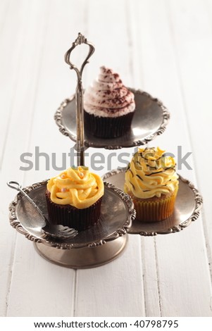 various of cup cakes are on the vintage food holder.