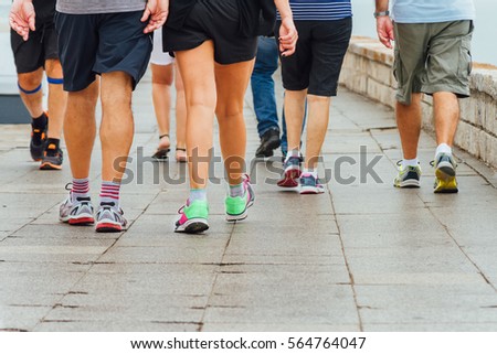 Several people walk down a sidewalk doing exercise