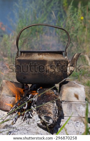 kettle  in soot hung over the fire in the campfire on fire on nature
