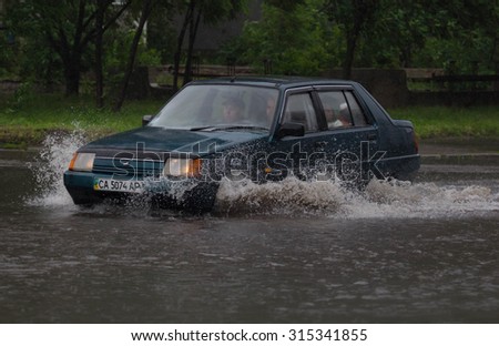 CHERKASSY, UKRAINE- JUNE 27, 2015: cars driving on a flooded road during a flood caused by heavy rain, in Cherkassy.