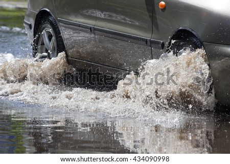 cars driving on a flooded road during a flood caused by heavy rain,