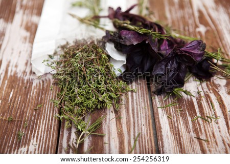 Bunch of dried thyme and basil over wooden table