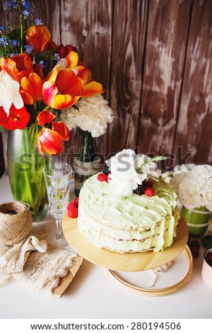 Mint cream cake decorated with flowers and berries on the stand