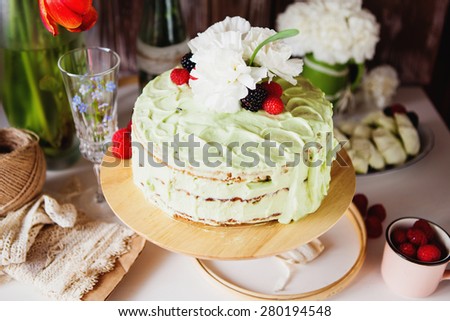Mint cream cake decorated with flowers and berries on the stand