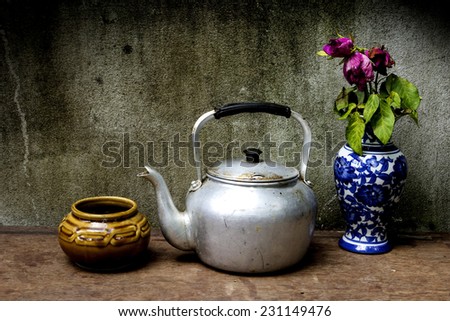 Old silver kettle and vase flower rose  placed on a wooden floor