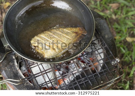 cooking fish frying in oil on the fire on camping  in the forest.