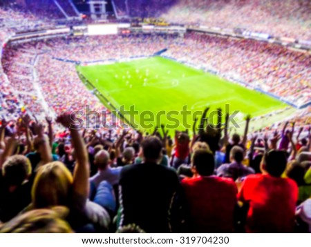 Football- soccer fans support their team and celebrate goal in full stadium with open air with nice sky.-blur picture.