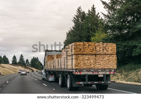 a truck  of lumbers moving on the road.