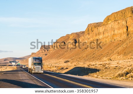 a big truck driving  in the sunset with mountain background.