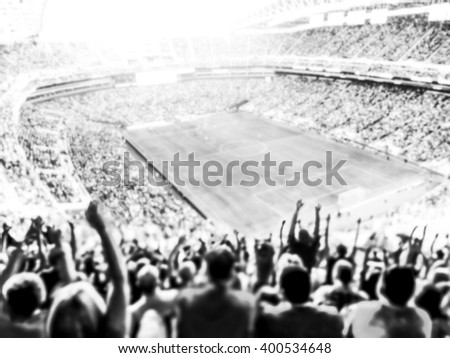 Football- soccer fans cheer their team and celebrate goal in full stadium with open air  with bright lighting beam     -blurred.