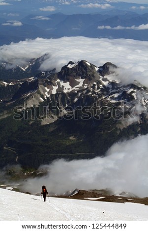 Man struggling to climb a mountain in the snow, with mountains and clouds in the background