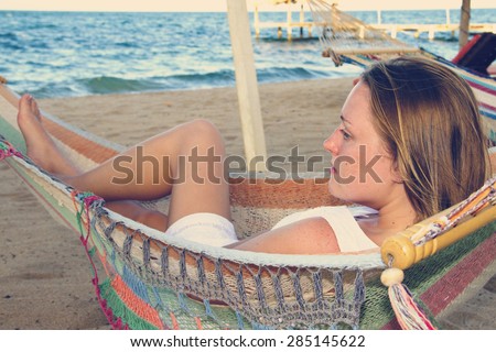 A beautiful woman in a white dress relaxing in a hammock