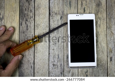smart phone and screwdriver on wood plank, top view, repair