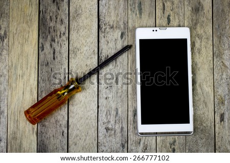 smart phone and screwdriver on wood plank, top view