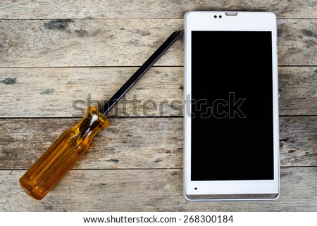 smart phone and screwdriver for repair on wood plank,  top view, black screen