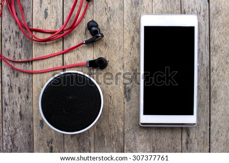 cellphone and bluetooth speaker and earphone on wooden background, listening set