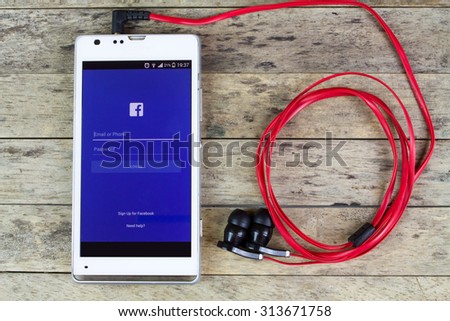 BUNG KAN, THAILAND - SEPTEMBER 02, 2015: using facebook by smart phone with earphones, facebook music stream