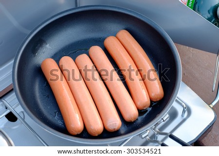 Hot dogs in frying pan on camp stove