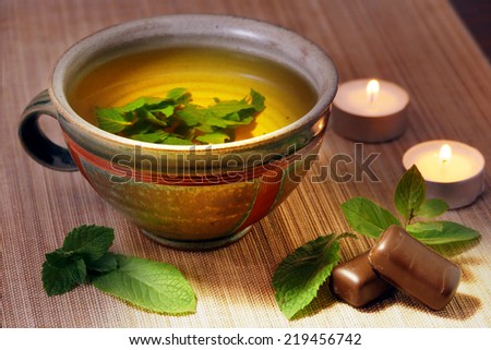 herbal tea from fresh mint leaves in a ceramic cup, chocolate, tea lights