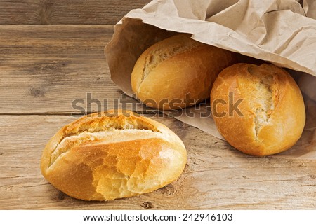 bread rolls in a paper bag on a rustic wooden table, fresh from the bakery for breakfast