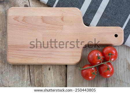 empty cutting board, kitchen towel and tomatoes on vintage wood, food background with copy space