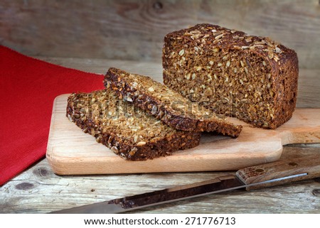 fresh dark rye bread with whole grain and sunflower seeds on a rustic wooden board