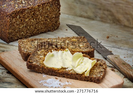 fresh dark rye bread with seeds, butter and salt on rustic wood, copy space
