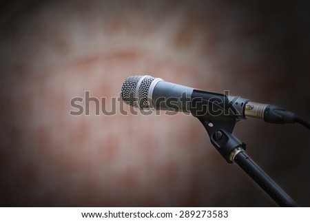 microphone in front of an old blurred brick wall with a light spot, narrow depth of field and copy space