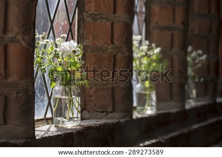 bouquets of white wild flowers in the windows of an old fortified monastery